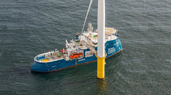 Windea La Cour alongside a wind turbine.