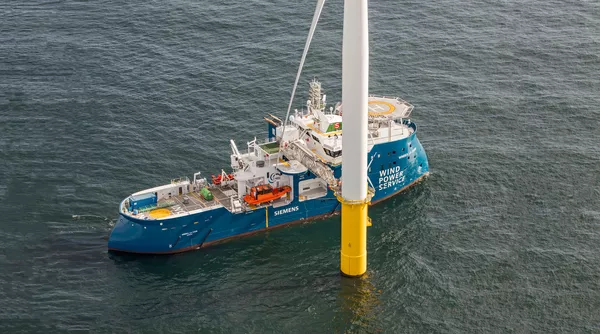 Windea La Cour alongside a wind turbine.