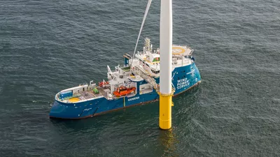 Windea La Cour alongside a wind turbine.